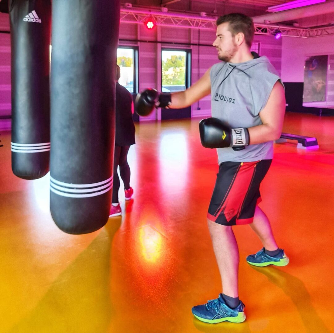 Een man die met bokshandschoenen op een bokszak slaat tijdens de les Power Boxing bij Arendse health club Oosterhout.
