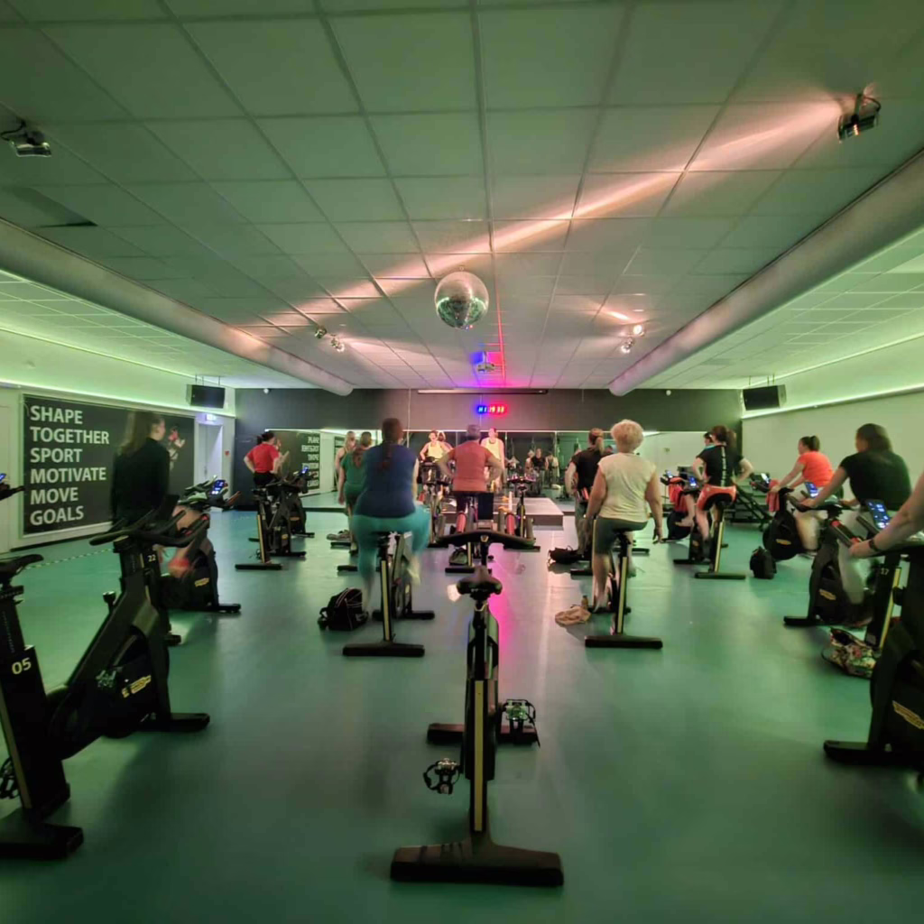 Het perspectief van iemand die meedoet aan een groepsles spinning bij Arendse health club