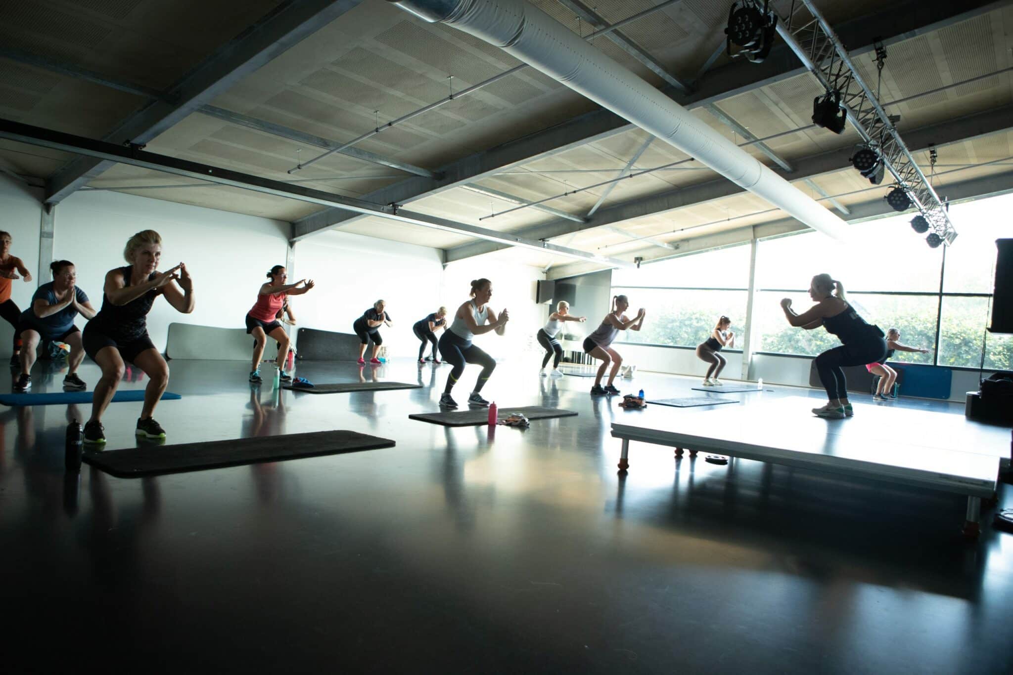 Een groep leden doet een squat tijdens een van de groepslessen bij Arendse health club
