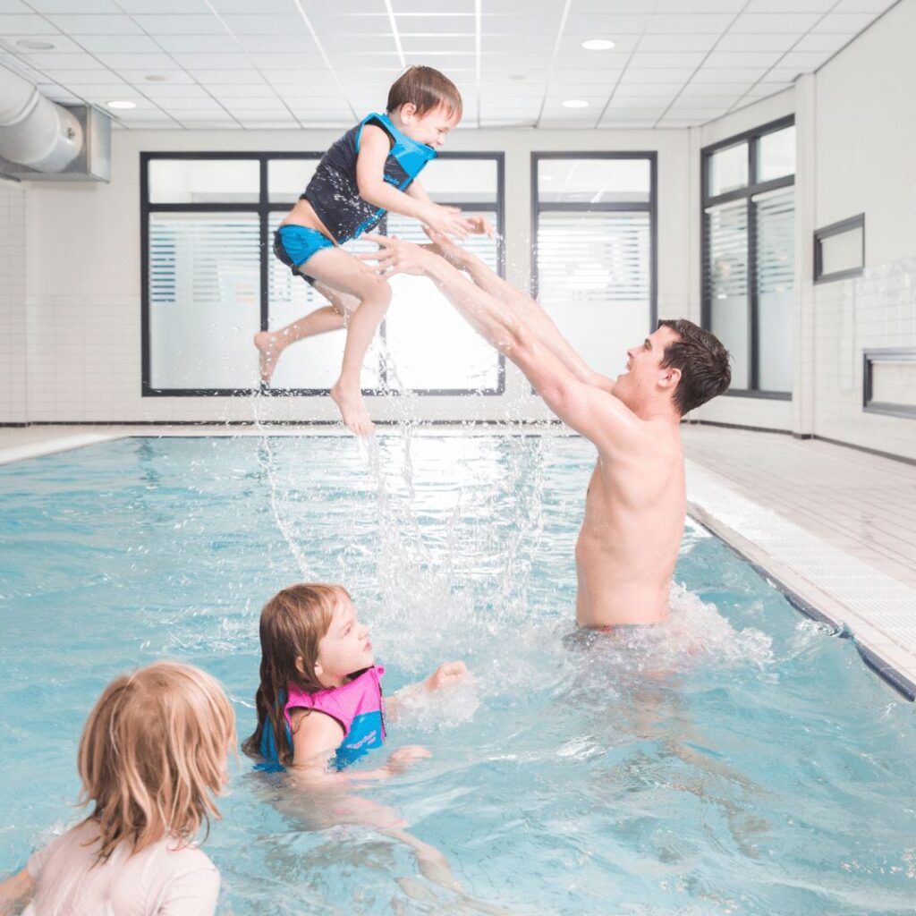 Een zwemdocent tilt een kind op onder het genot van het kindje