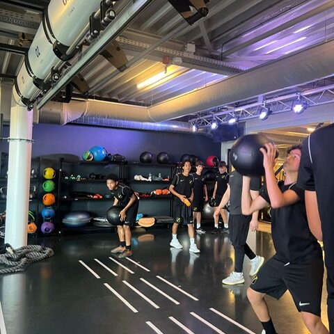 Een groep voetballers van NAC die de oefening Wall Balls aan het uitvoeren zijn.